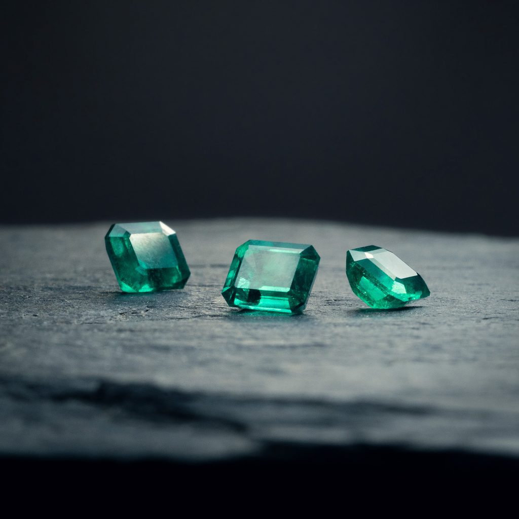 Drei rechteckig geschliffene, hochwertige 1 Carat Smaragde in sattem Grün auf dunklem Stein-Grund.